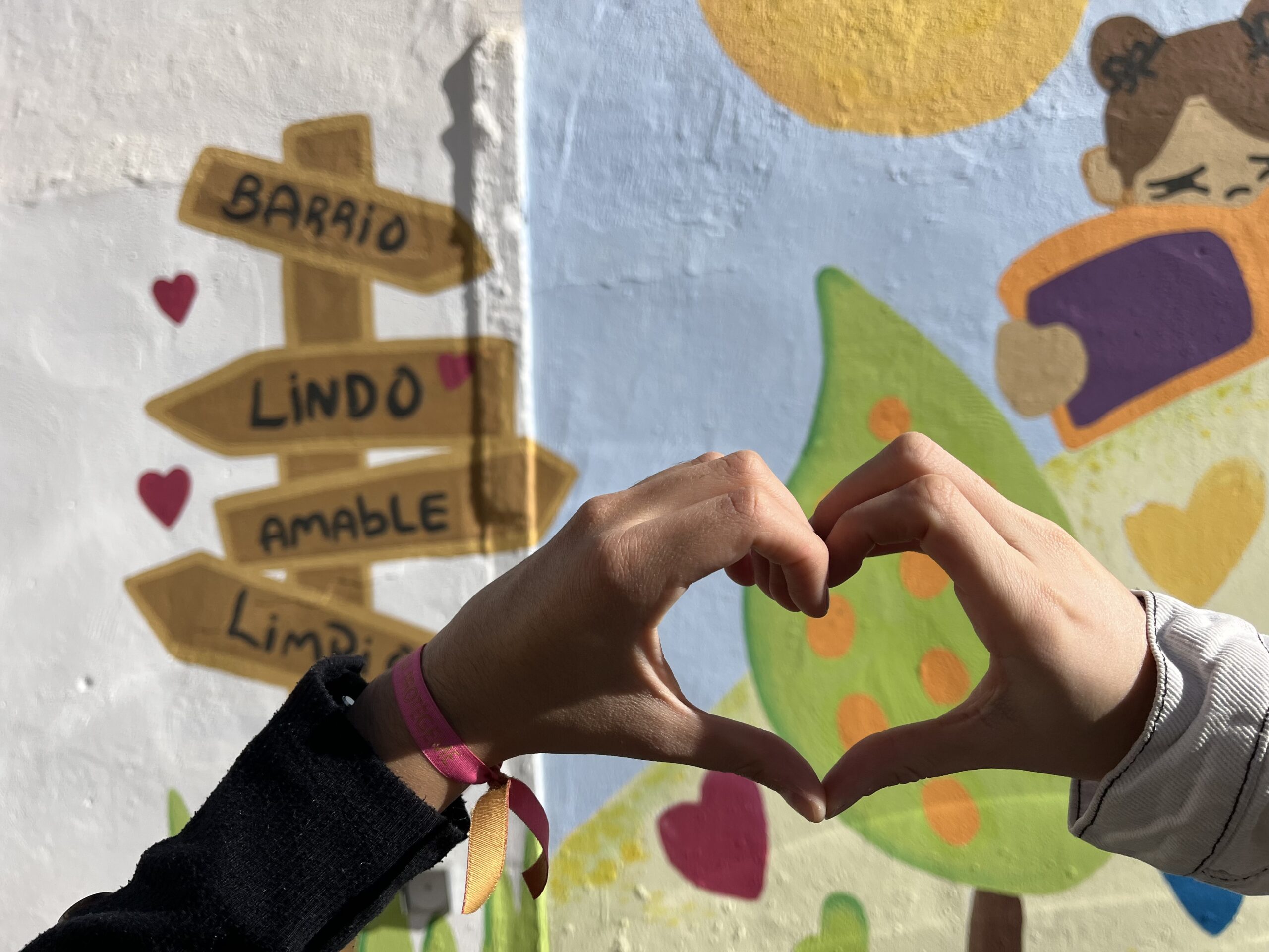 Manos en forma de corazón con mural al fondo