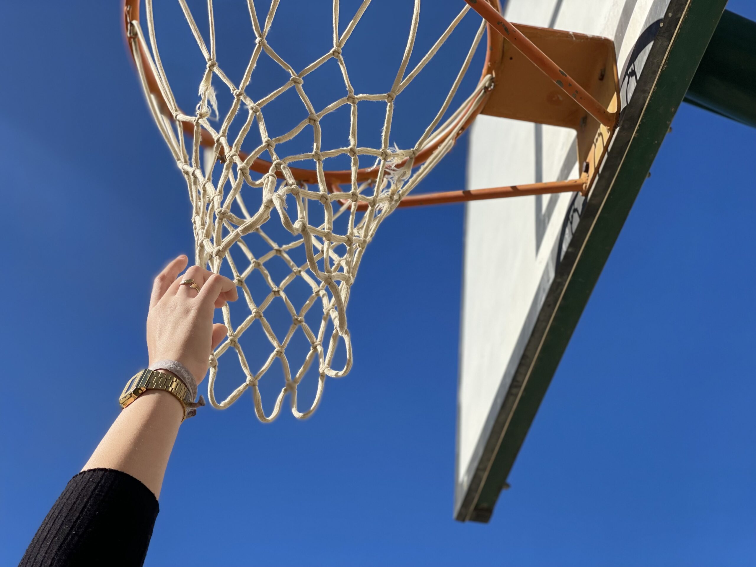 Una mano intenta alcanzar la red de una canasta de baloncesto